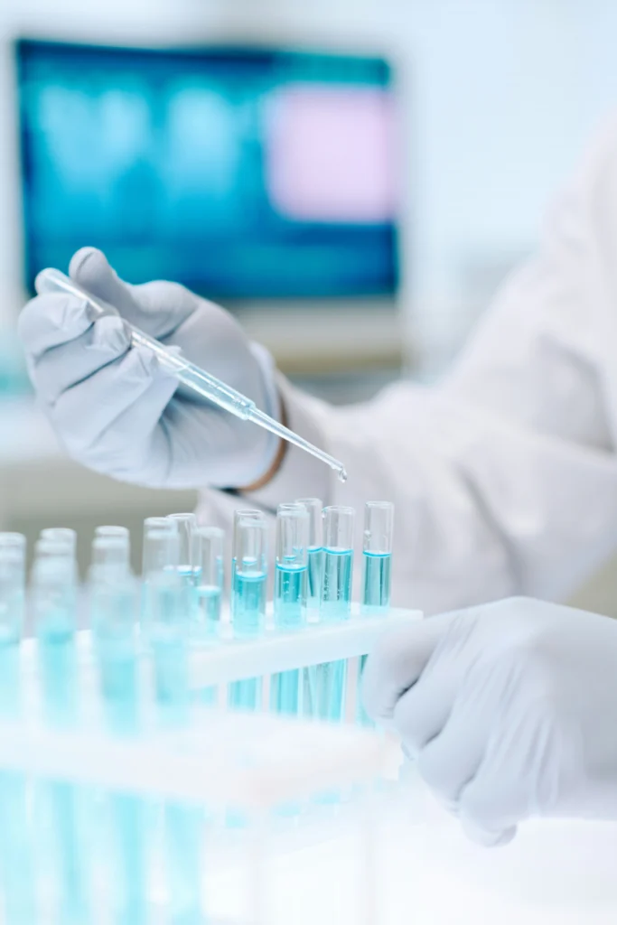 Tecnico di laboratorio che trasferisce un liquido in provette con una pipetta durante un test scientifico